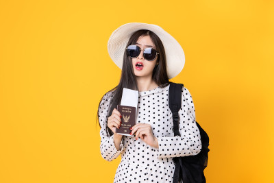 夏日休闲装的女游客。亚洲微笑女子。以黄色为背景出国旅行的乘客。一个亚洲女人要去度暑假。旅行有趣的旅行