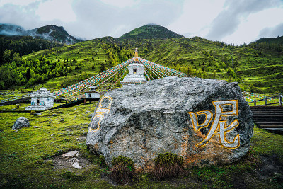 中国四川省四姑娘山双桥沟的宝塔和祈祷者。西藏白塔、经幡、玛尼石