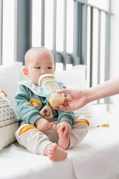 亚洲婴儿坐在凸窗上吃牛奶