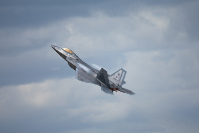 F-22猛禽在高G机动中，机翼上方形成凝结尾迹，在云层中可见热急流