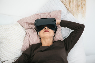 戴着虚拟现实眼镜的老妇人。使用现代科技的老人。