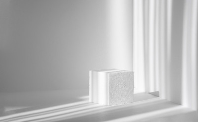 3d讲台，为包装和化妆品演示。白色的泡沫立方体映衬着干净的墙壁，阴影在刺眼的阳光下，像条纹一样