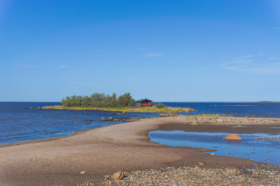 波罗的海风景如画的海岸，在蓝天下的沙滩后面的岛上有一座红色的小别墅