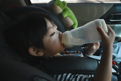 小男孩在汽车安全座椅上吮吸牛奶