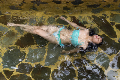 西班牙妇女漂浮在温泉在蓝色泳衣-女人在温泉自然池-健康的身体在夏天在危地马拉全身