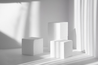 3d讲台，为包装和化妆品演示。三个不同高度的白色泡沫聚苯乙烯立方体，映衬着干净的墙壁，在刺目的阳光下