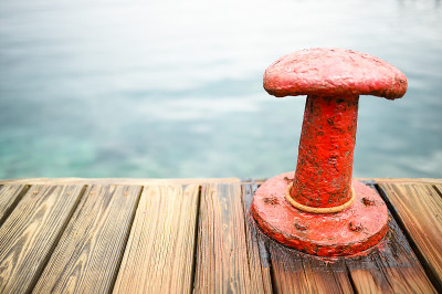 Red bollard with a mooring rope on the pier at the