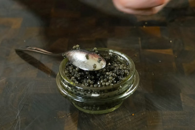 用勺子在玻璃罐中搅拌黑鱼子酱。