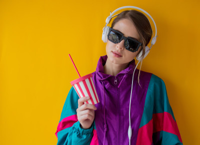 穿着90年代风格的衣服，戴着耳机和杯子