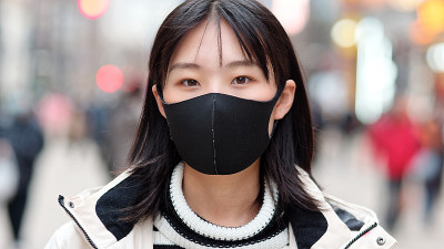 在上海南京路步行街，年轻的中国女孩戴着外科口罩对抗疾病的特写。