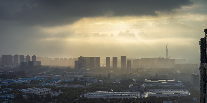太阳在雨中穿过云层形成潮汐效应的城市
