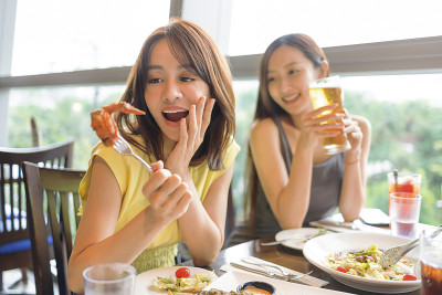 快乐的年轻女子在餐厅享受美食和饮料