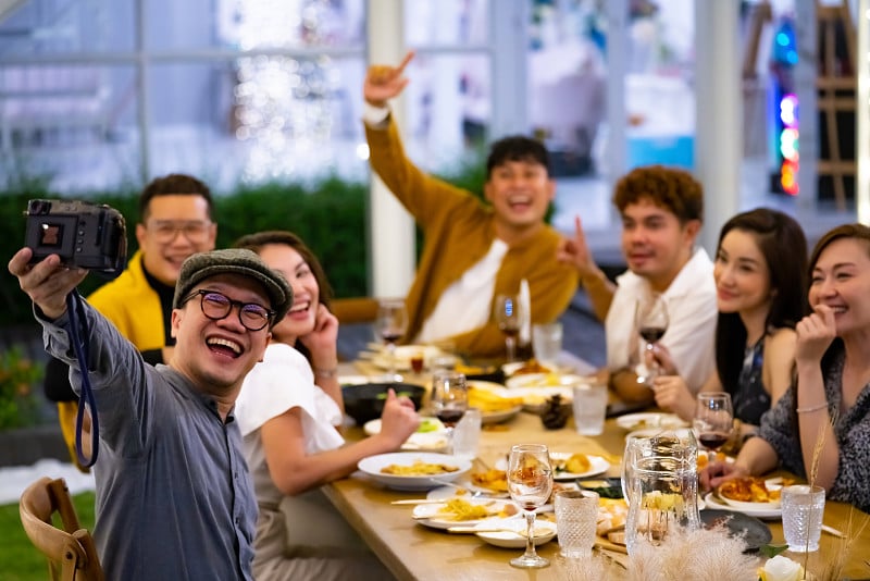 一群多元化的亚洲朋友在花园的晚宴上一起用数码相机拍照