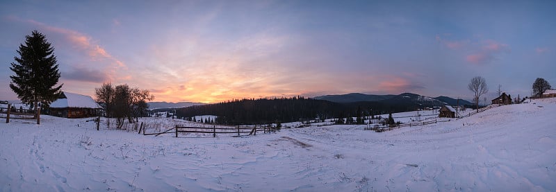 小高山村庄和冬季雪山在第一轮日出阳光的周围，沃罗年科，喀尔巴阡，乌克兰。