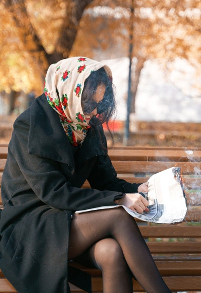 一个穿着黑外套、戴着黑眼镜的女孩正在烧报纸
