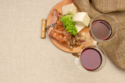 肉、奶酪和酒杯放在铺着亚麻布的桌子上