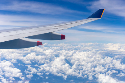 飞机机翼窗外多云的天空背景，旅游度假概念