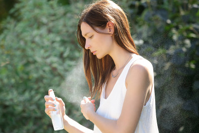 女人用热水提神抵御夏日热浪。女士喷身体或头发喷雾，夏日护肤和护发理念。