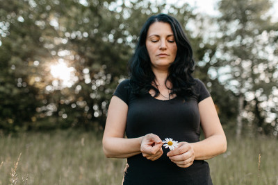 一个女人正在摘下一朵白色雏菊的花瓣。