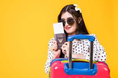 夏日休闲装的女游客。亚洲微笑女子。以黄色为背景出国旅行的乘客。一个亚洲女人要去度暑假。旅行有趣的旅行