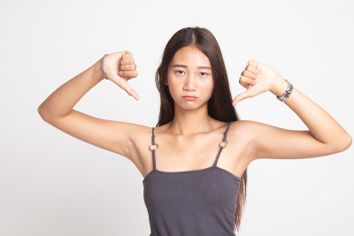 不快乐的亚洲女孩双手大拇指向下。