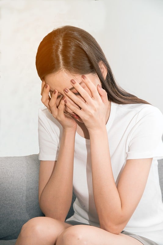 患有严重偏头痛的亚洲妇女双手抱头。