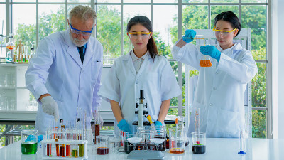 一队身穿白袍的教授、研究员、科学家，用桌上的科学设备配制试验化学液体。与浓度。与背景室内白色实验室。