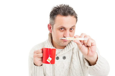 寒冷的人拿着杯子和显示温度计