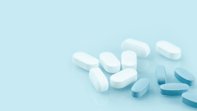 几片白色和蓝色的药片或药丸在桌子上。医学和药学