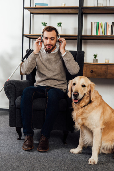 视障人士在家边听金毛猎犬边戴耳机听音乐
