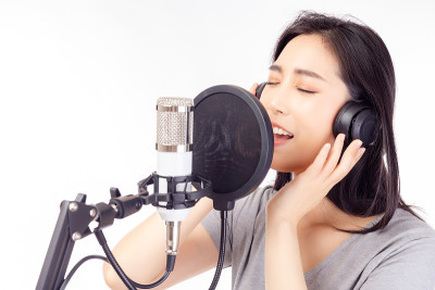 歌手女歌手在录音室唱歌，使用麦克风，流行滤镜和耳机录制音乐歌手年轻的女性表演和唱歌在音乐工作室孤立的