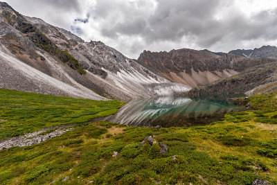 山、湖和美丽的高山。大理石山倒映在水中。地球上有许多绿色植物。天空阴云密布。水平的。