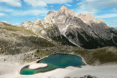 A small, navy blue lake at the bottom of the valle