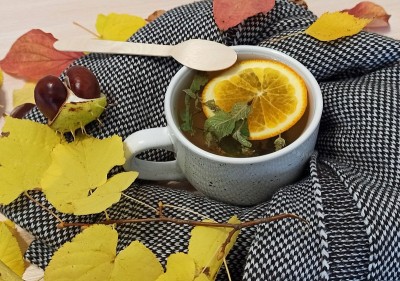 热腾腾的凉茶，橙黄色的叶子环绕在桌子上，秋天温馨的茶会概念