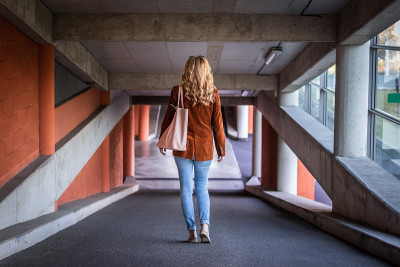 时尚的年轻女子在公共停车场散步。
