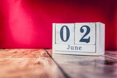 6月2日。月二日，日历放在商务办公室的桌子上，工作场所以鲜艳的栗色为背景。夏天的时间