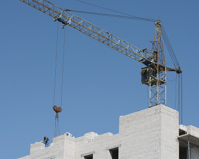 老式建筑起重机正在吊装建筑材料。多层建筑的建造。