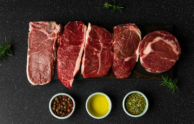 选择生牛肉肉排，以黑石为背景。纽约striploin牛排，顶级刀片，肋眼，和其他切肉。