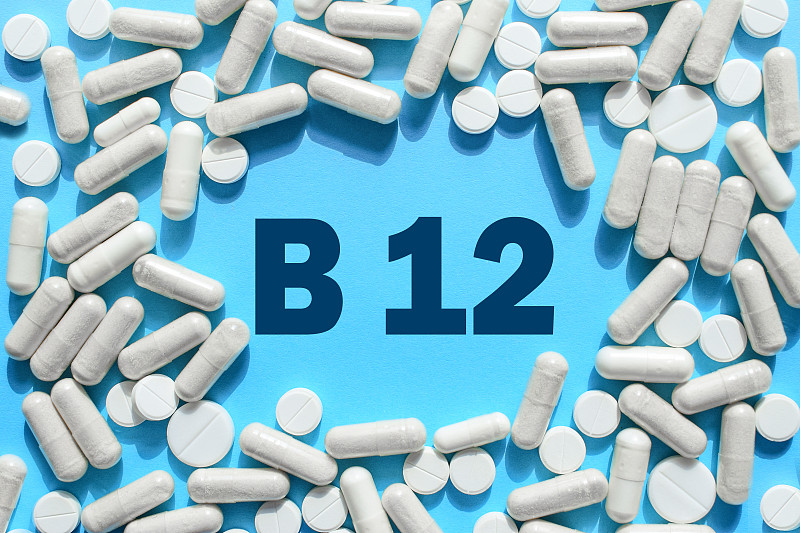 维生素B12文字在白色胶囊框架在蓝色背景。氰钴胺素药片。膳食补充剂和药物