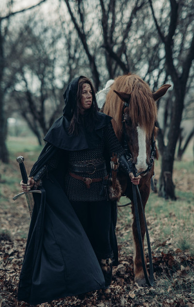 中世纪武士形象中的女子手持长剑牵着她的马。