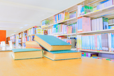 学校图书馆的桌子上放着旧书和成堆的论文。模糊的书架背景。教育学习理念用拷贝空格加文字