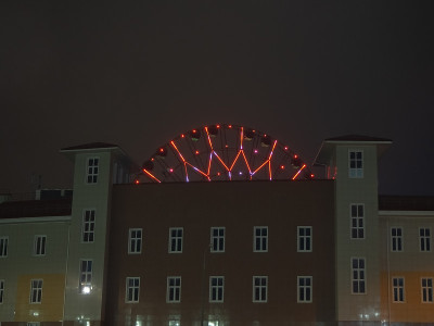 一个建筑物的夜景照片，在两座塔之间的中心有一个发光的摩天轮