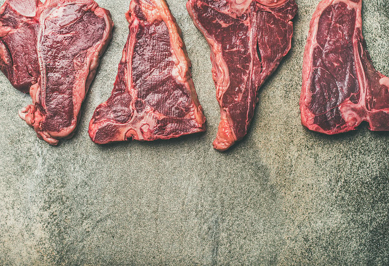 平铺的新鲜生牛肉牛排在混凝土背景