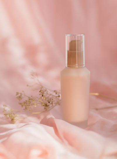 化妆品瓶子霜乳液粉红色的织物背景