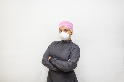一名女医生戴着n95口罩，穿着专用手术服抗击COVID-19