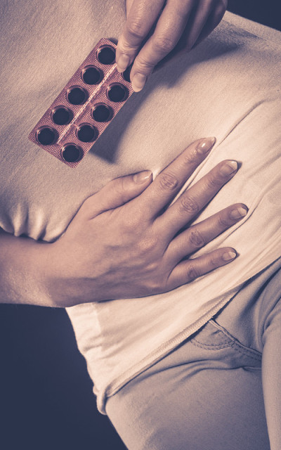 肚子疼的女人拿着药片