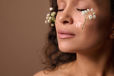 特写美丽的女人的脸与白色的枝在脸颊上的Gypsophila。春天，女性气质，性感，自然美丽的人们和妇