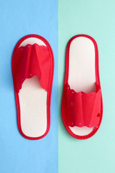 Red one-off slippers for hotel on a colored backgr