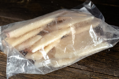 大大小小的冻虾有头或没有头，粉红色，有触手，胡子和腿在一个包裹用白霜，切在一个贞洁的桌子黑板切割桌子