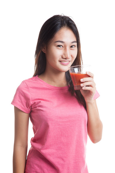 年轻的亚洲女子喝番茄汁